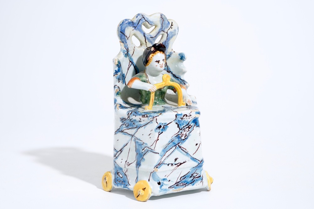 A Dutch Delft polychrome group of a child seated on a toilet, 18th C.