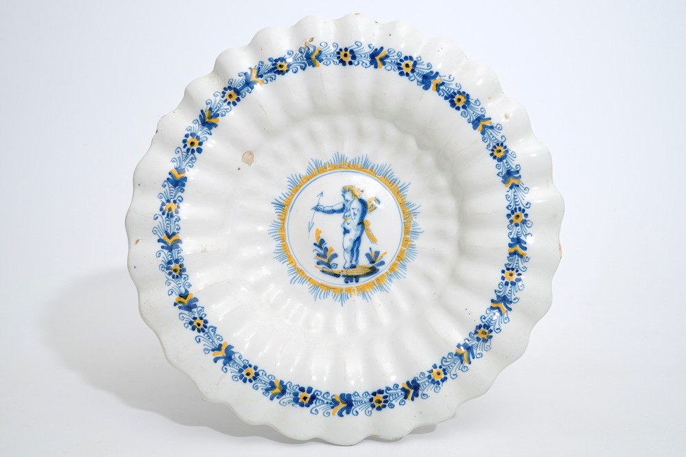 A Dutch Delftware gadrooned dish with a putto in blue and yellow, Haarlem, 17th C.