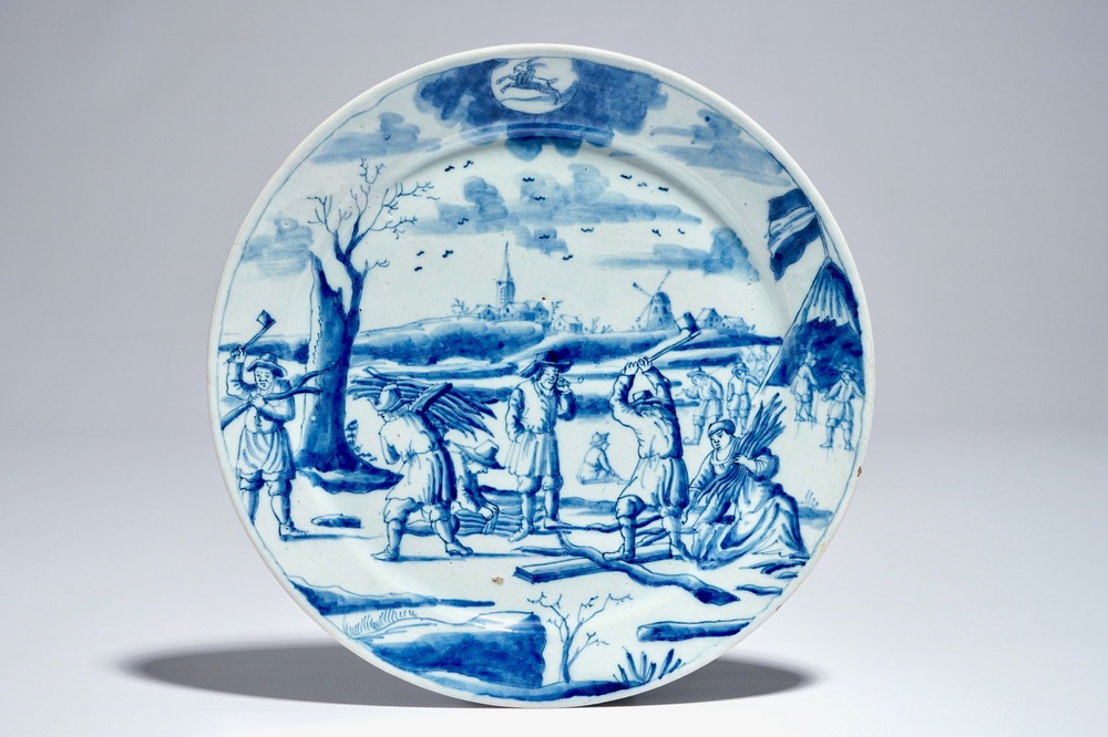 A Dutch Delft blue and white plate with lumberjacks from the 'Zodiac' series, early 18th C.