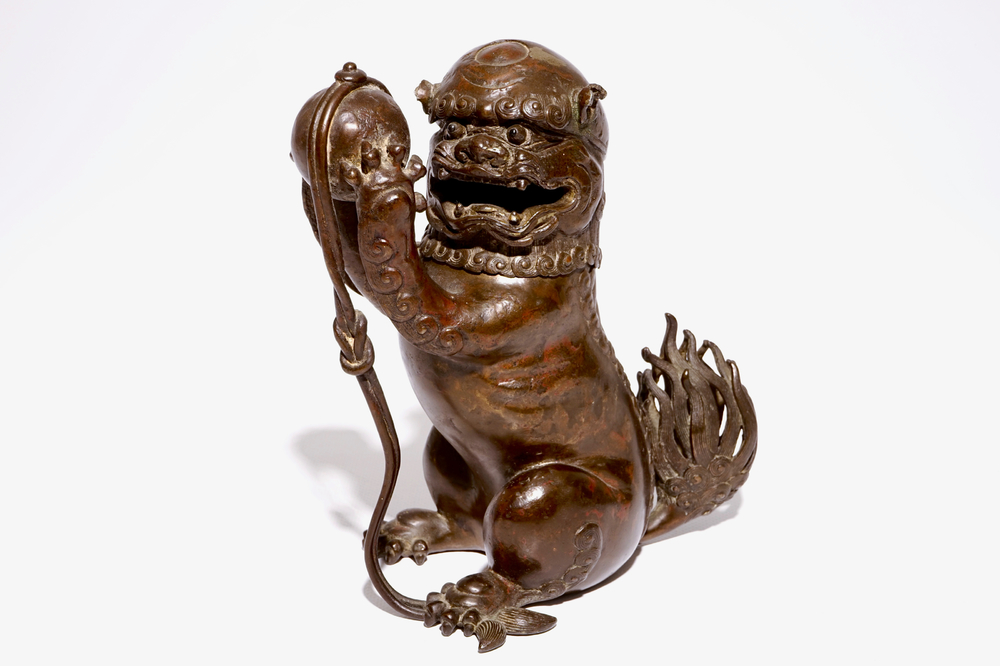 A Chinese lacquered bronze censer modelled as a buddhist lion with a brocade ball, Ming