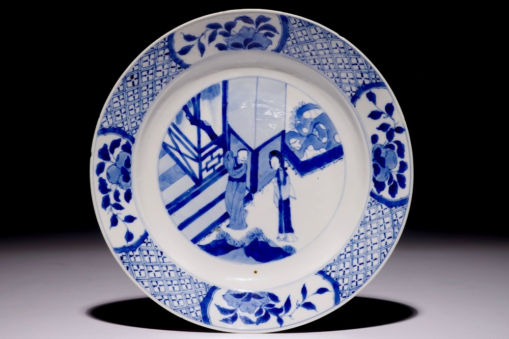 Une assiette en porcelaine de Chine bleu et blanc &agrave; d&eacute;cor de personnages dans un jardin, marque et p&eacute;riode de Kangxi