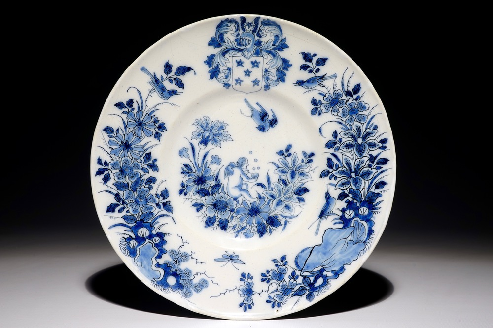 A Dutch Delft blue and white armorial plate with a putto, 17th C.
