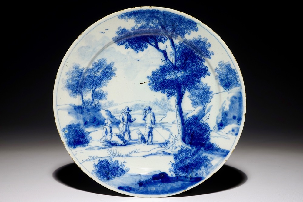 Een fijn blauw-wit Delfts bord met twee mannen en een vrouw bij een boom, begin 18e eeuw