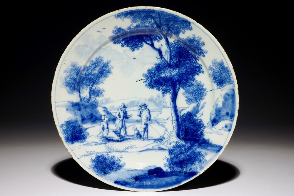 A fine Dutch Delft blue and white plate with two men and a lady below a tree, early 18th C.