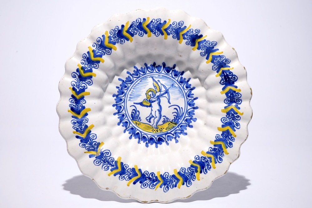 A Dutch Delftware gadrooned dish with a putto in blue and yellow, Haarlem, 17th C.