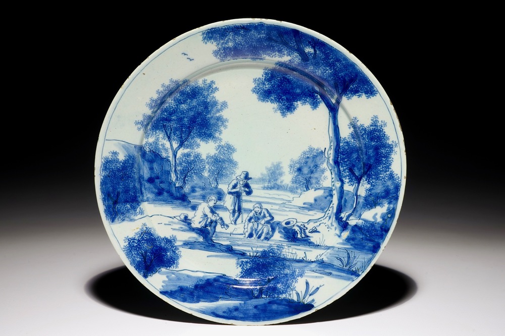 A fine Dutch Delft blue and white plate with men near a river, early 18th C.