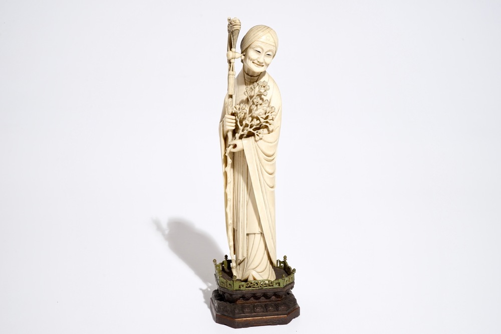 Een Chinese ivoren figuur van een dame met staf, op houten basis, 19e eeuw