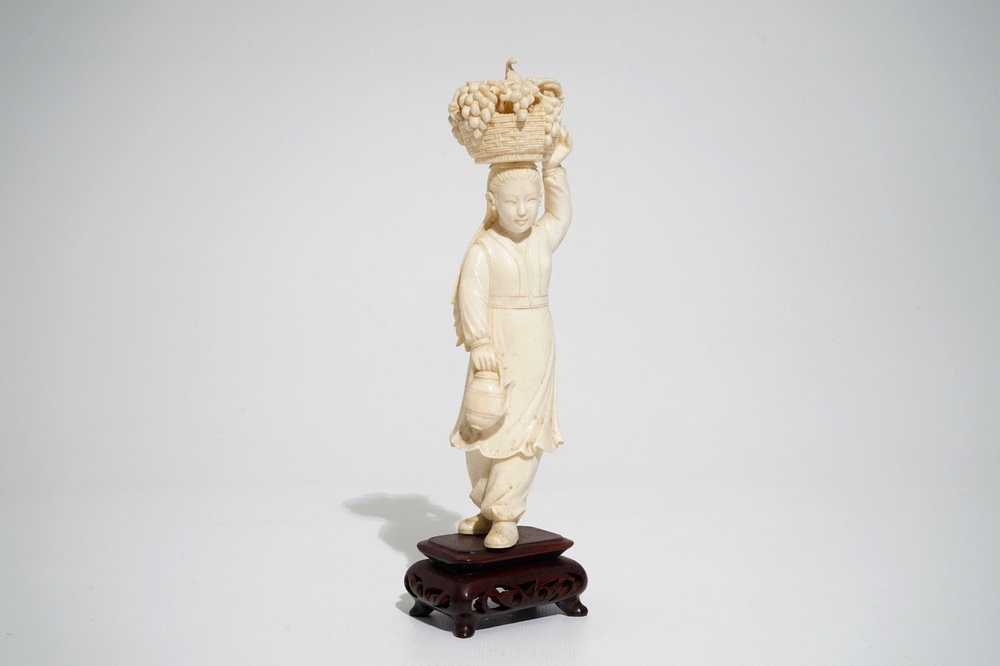 A Chinese carved ivory figure of a lady with a fruit basket, 2nd quarter 20th C.