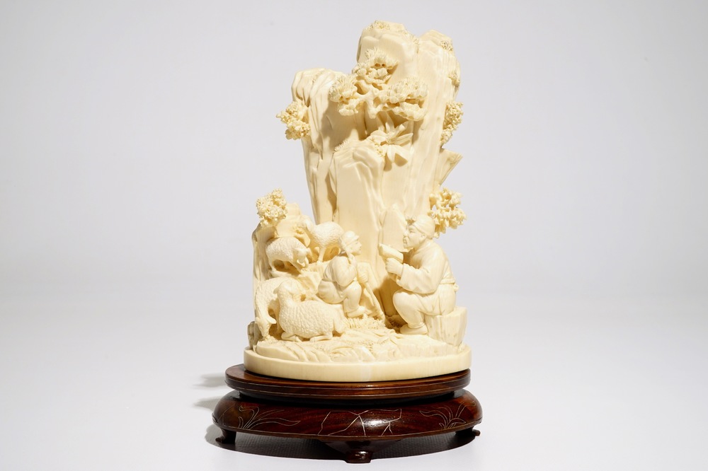 A Chinese ivory group with figures and sheep on wooden stand, 2nd quarter 20th C.