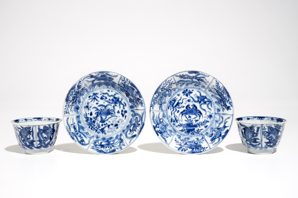 A pair of Chinese bleu and white cups and saucers with crabs and fish, Kangxi