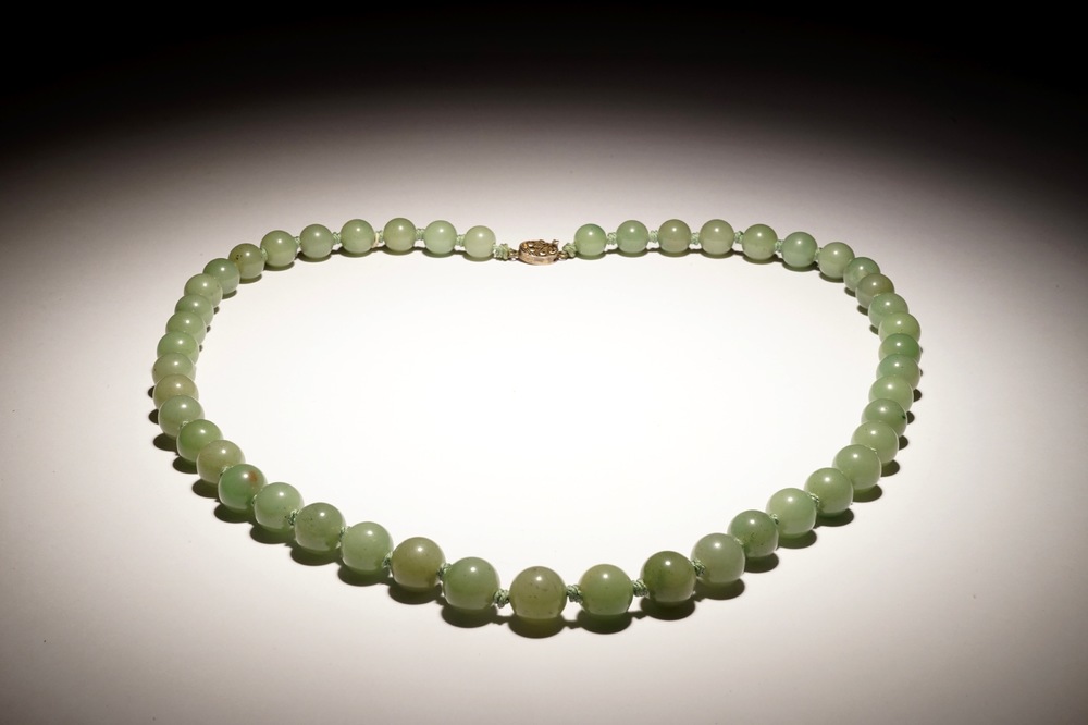 A Chinese green jade beads necklace with silver lock, 19/20th C.