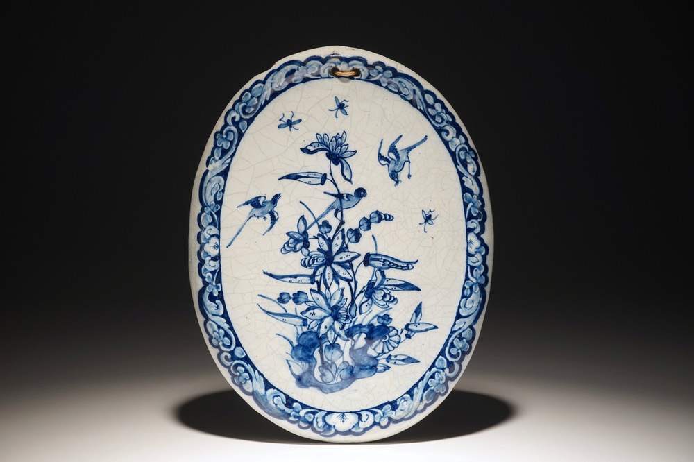 Une plaque ovale en fa&iuml;ence de Delft bleu et blanc &agrave; d&eacute;cor d'oiseaux parmi fleurs, 18&egrave;me