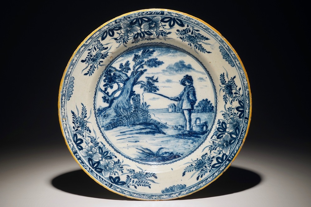 Un plat en fa&iuml;ence de Delft bleu et blanc figurant &quot;Le jeune p&ecirc;cheur&quot; d'apr&egrave;s Bloemaert, 18&egrave;me