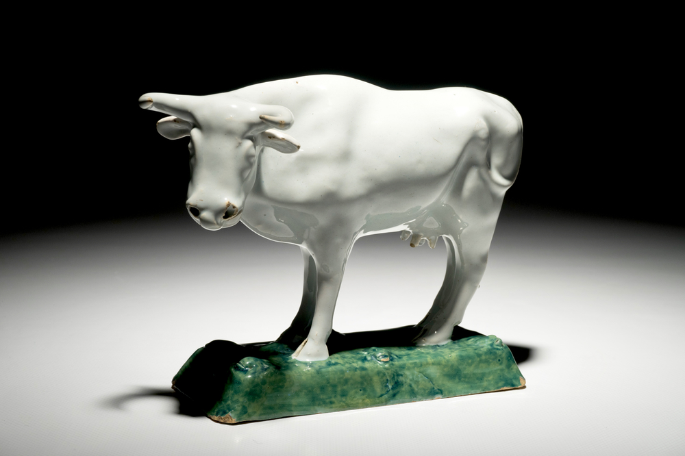 A white Dutch Delft model of a cow on a green base, 18th C.