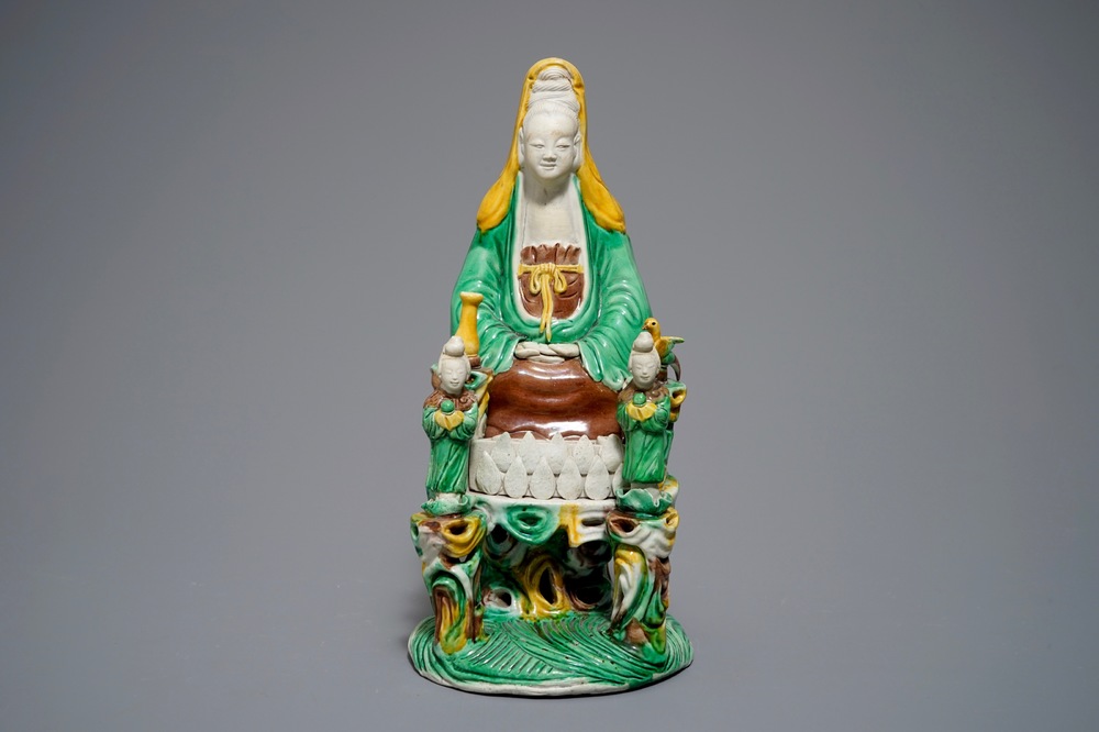 A Chinese verte biscuit group of Guanyin on a lotus throne, 18th C.