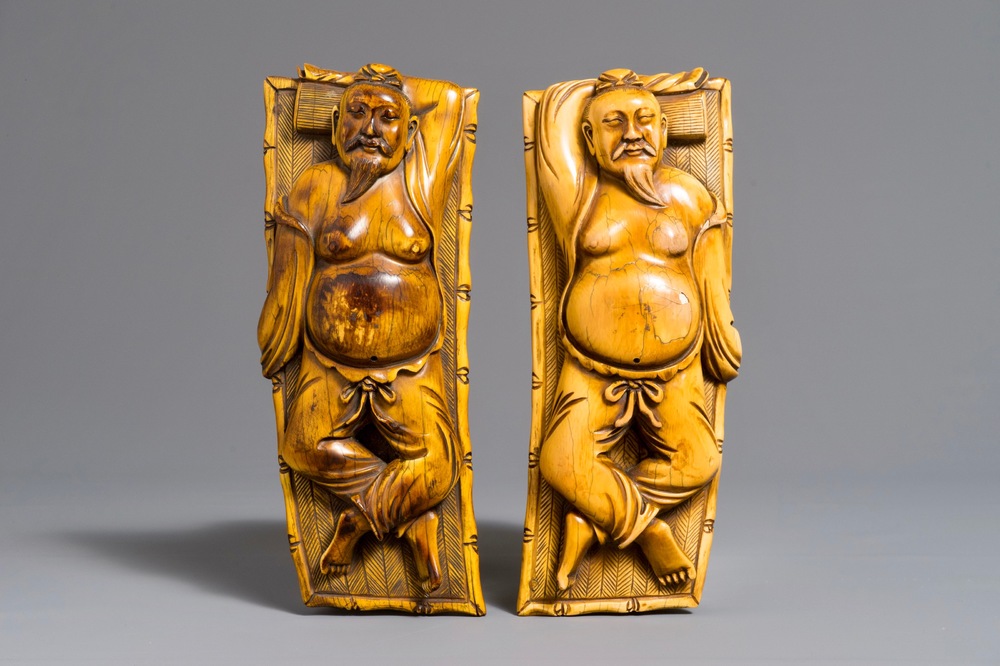 A pair of Chinese carved ivory figures of resting men on a bed, 19th C.