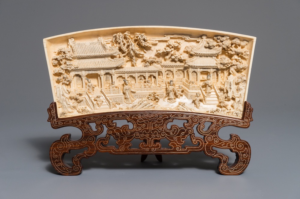 A Chinese carved ivory panel with figures in a landscape on inlaid wooden stand, first half 20th C.