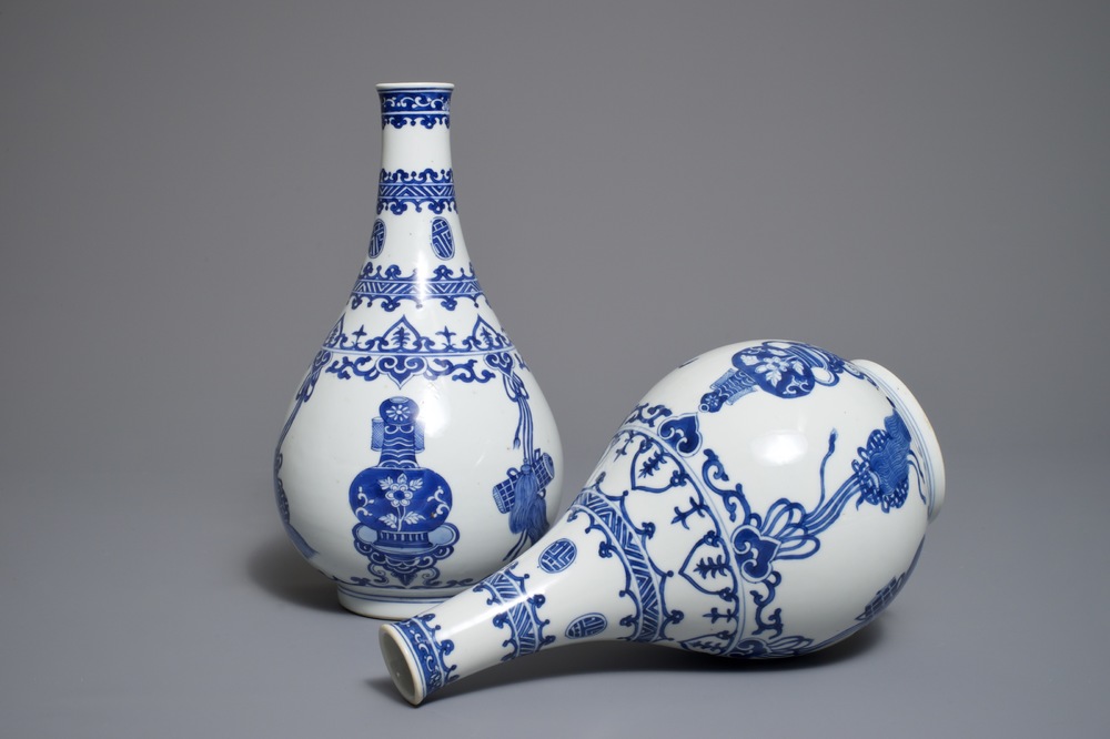 A pair of Chinese blue and white bottle vases with ribbons and precious objects, Kangxi