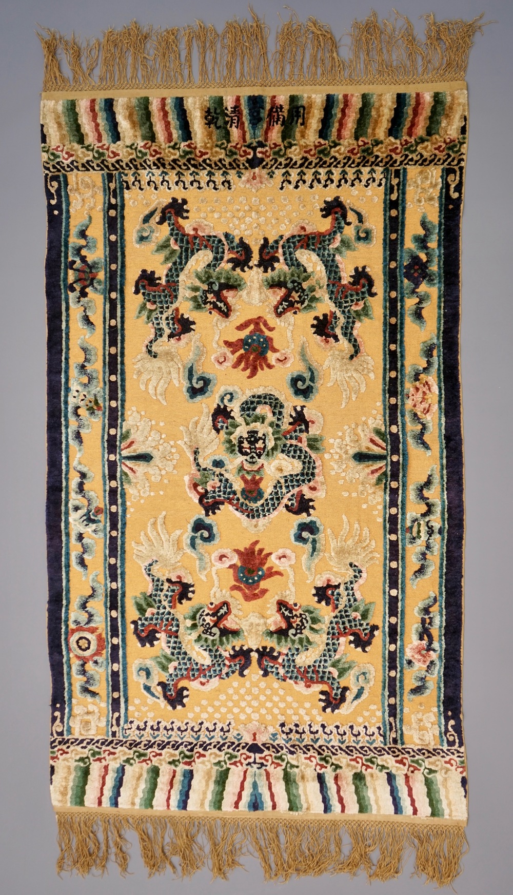 A Chinese silk and gilt-thread 'five dragon' carpet with inscription, 19th C.