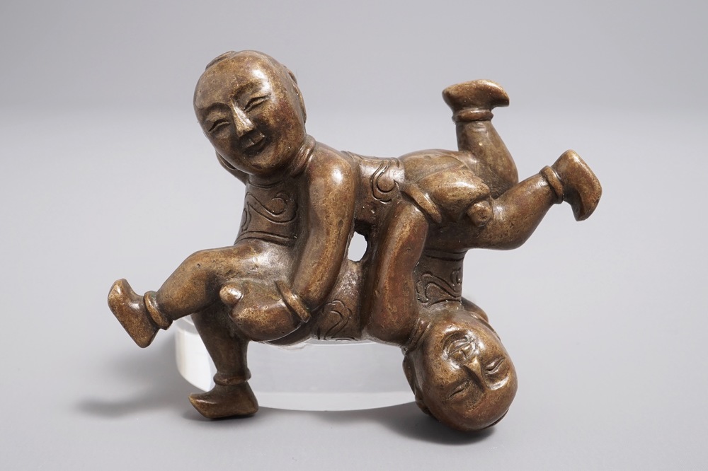 A Chinese bronze scroll or paper weight shaped as a pair of wrestling boys, 18/19th C.