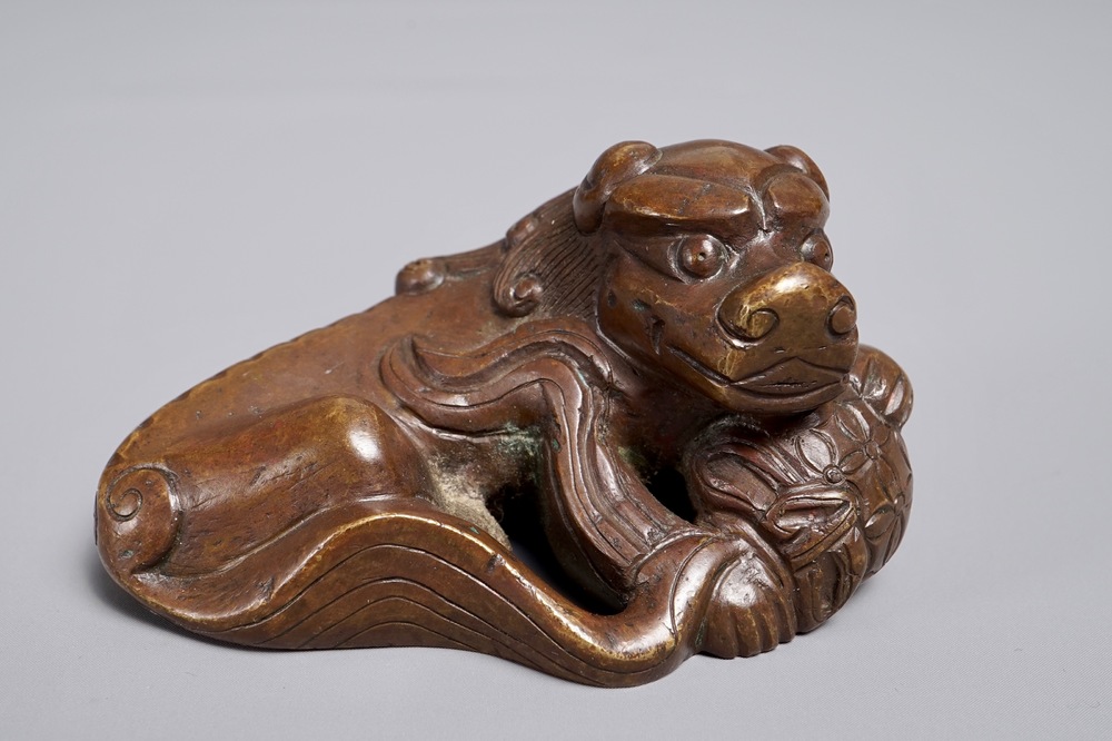 A Chinese bronze scroll or paper weight shaped as a Buddhist lion or Shishi with a ball, 17/18th C.