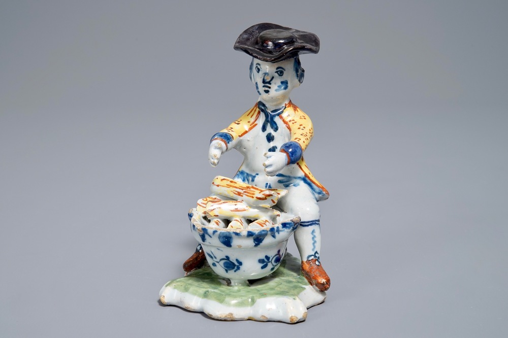 A polychrome Dutch Delft model of a man near a stove, 18th C.