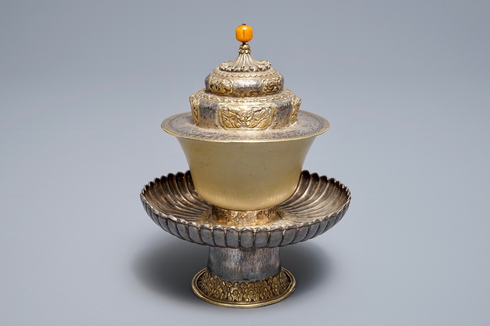 A Tibetan ritual jade bowl on parcel-gilt silver stand with amber finial, 19th C
