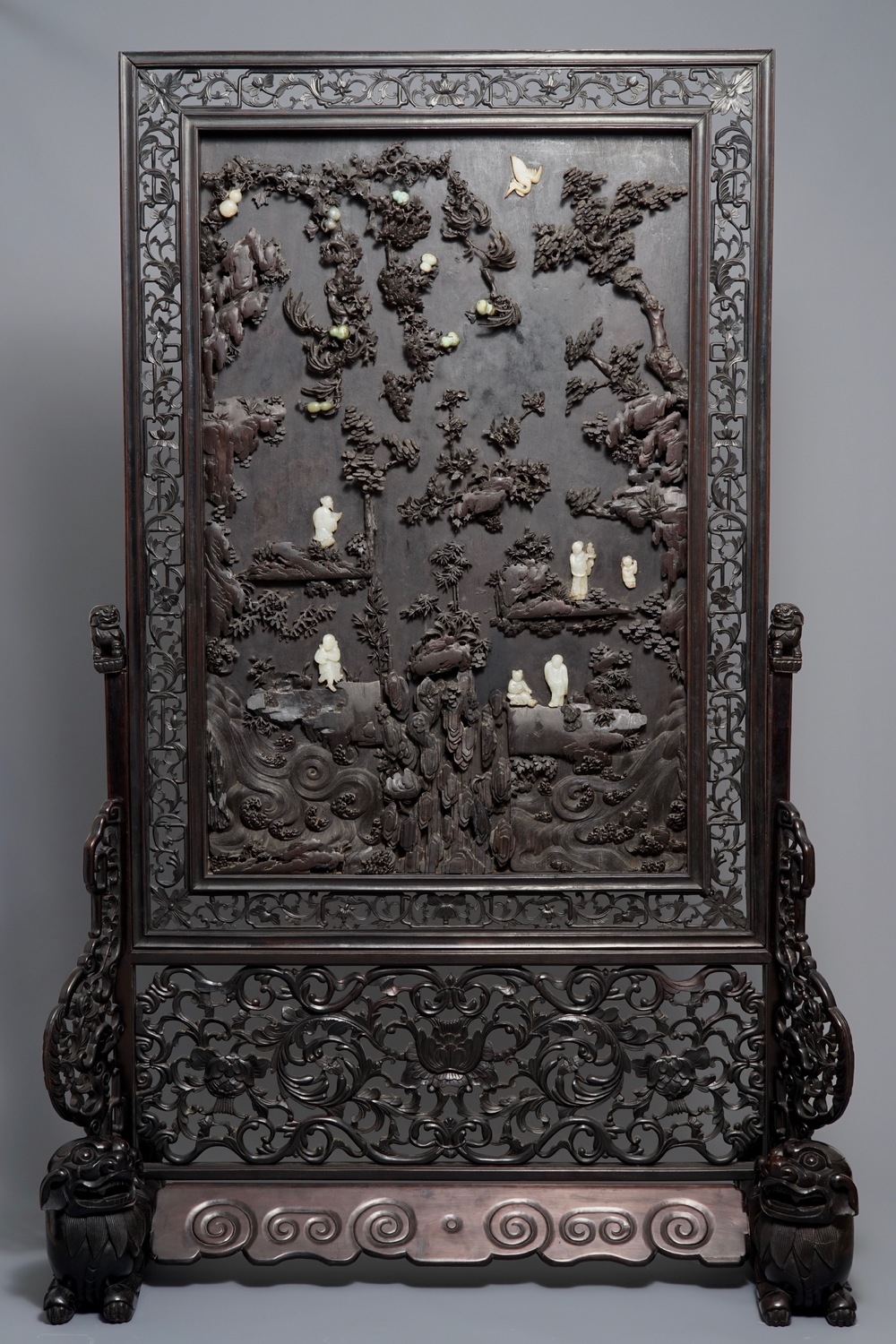 A large Chinese carved zitan wood panel with jade and turquoise, set in a hongmu wood frame and stand, Qianlong