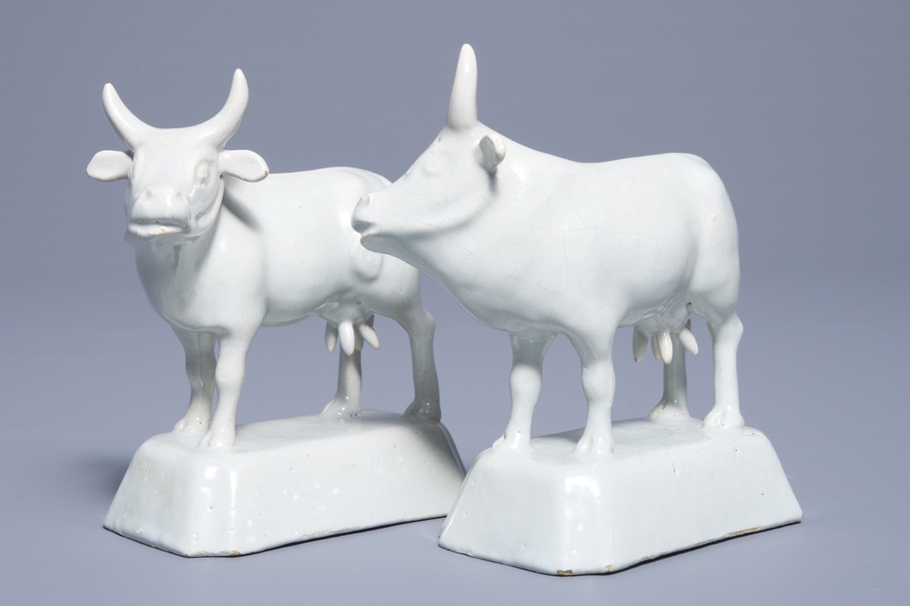 A pair of white Dutch Delft models of cows on bases, 18th C.