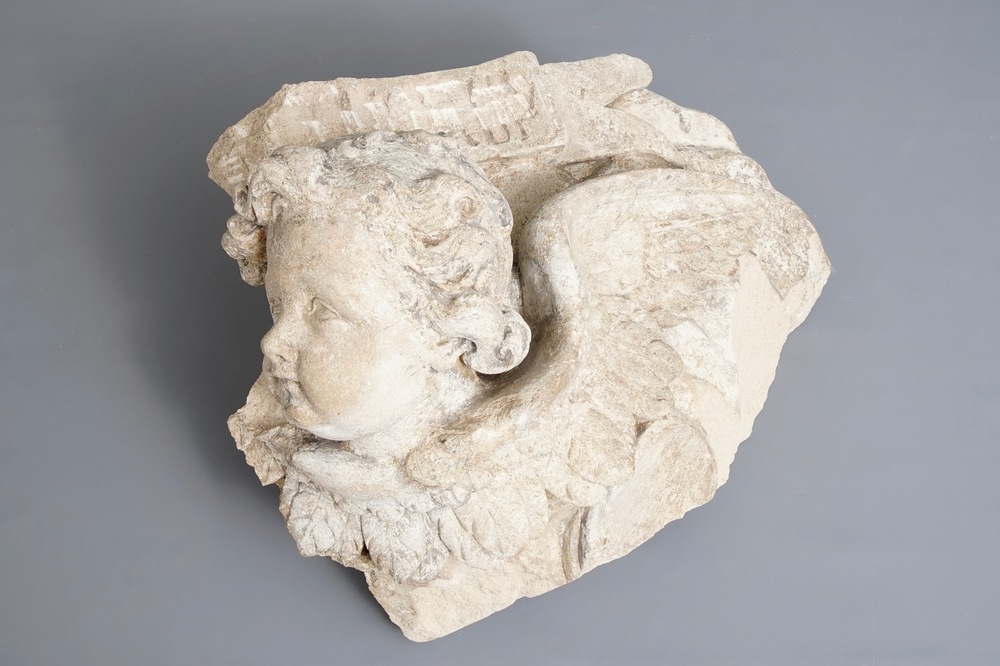 A carved stone wall fragment of a cherub's head with wing, 17/18th C.