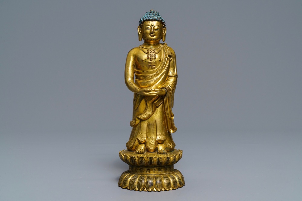 Een Chinese verguld bronzen figuur van een staande Boeddha met inscriptie, Qianlong