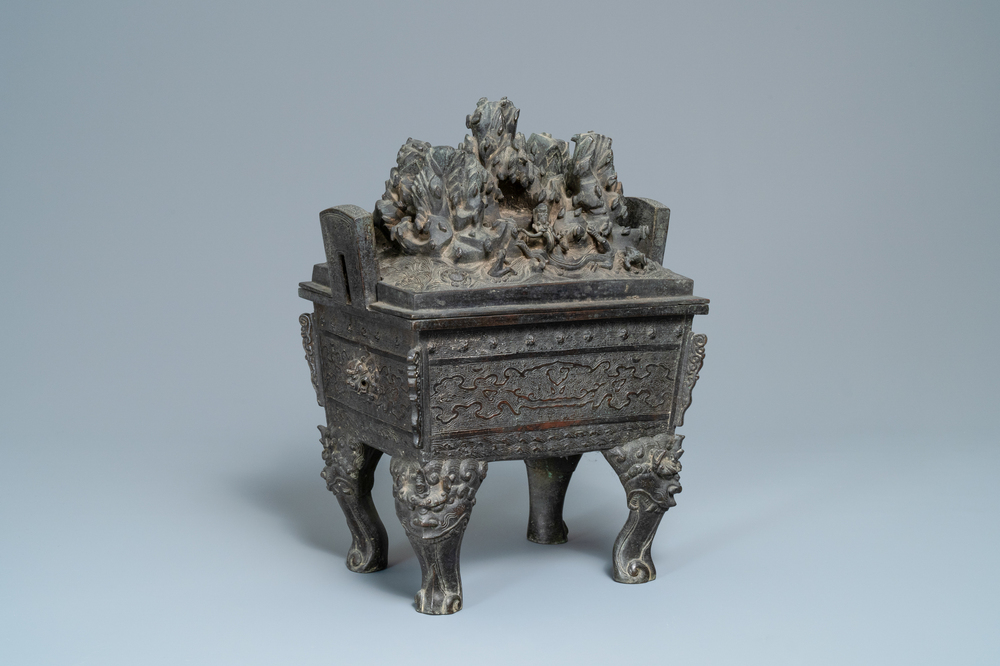A large Chinese bronze censer and cover with animals near a hilly landscape, Ming