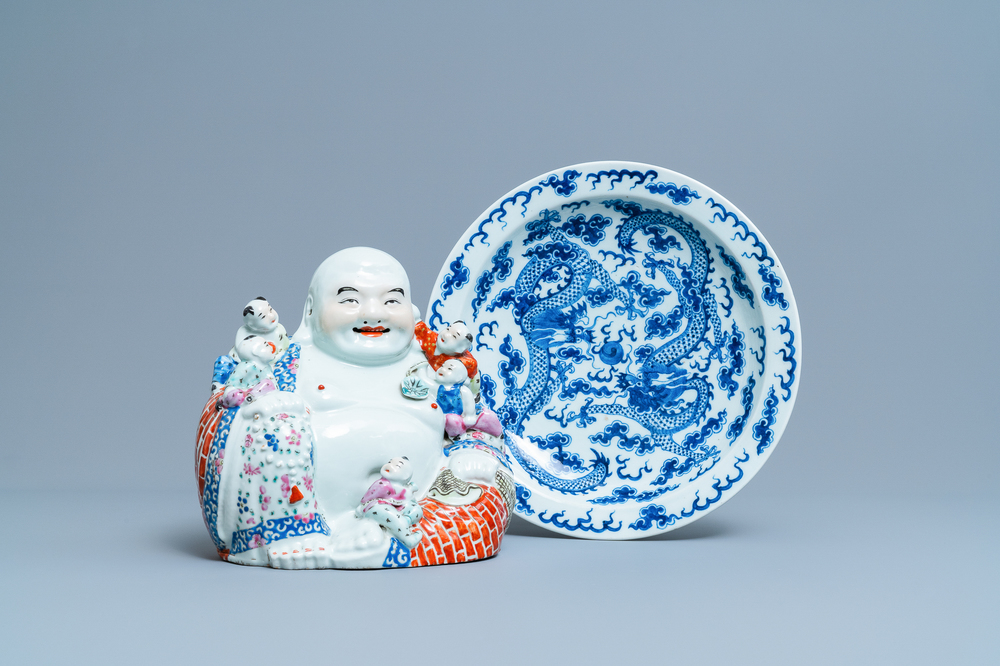 Un plat en porcelaine de Chine en bleu et blanc et une figure de Bouddha en famille rose, 19&egrave;me