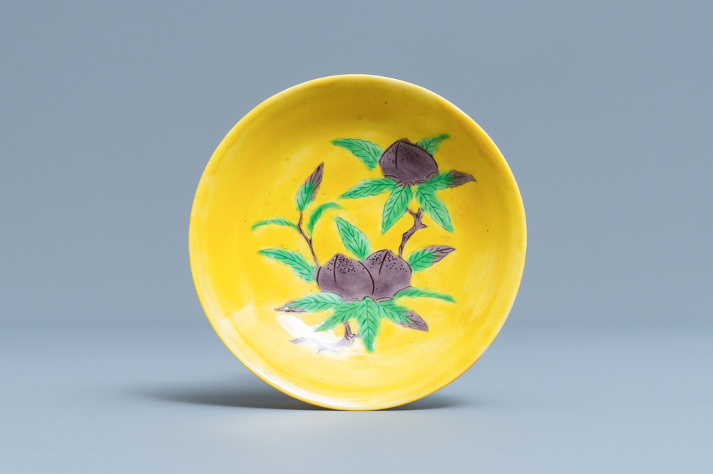 A Chinese yellow-ground green and aubergine 'peaches' saucer, Kangxi