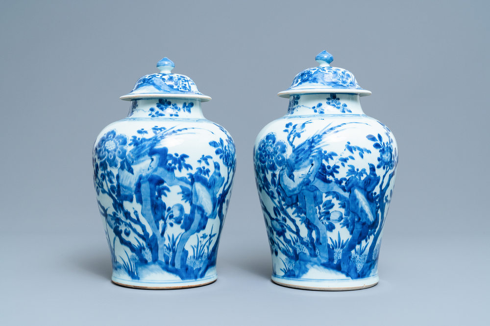 A pair of Chinese blue and white baluster vases and covers with birds in a rocky landscape, Kangxi
