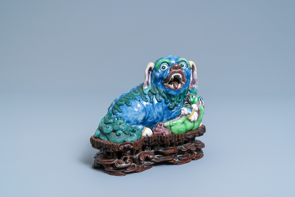 A Chinese porcelain 'Buddhist lion and cub' group on carved wooden stand, 19th C.