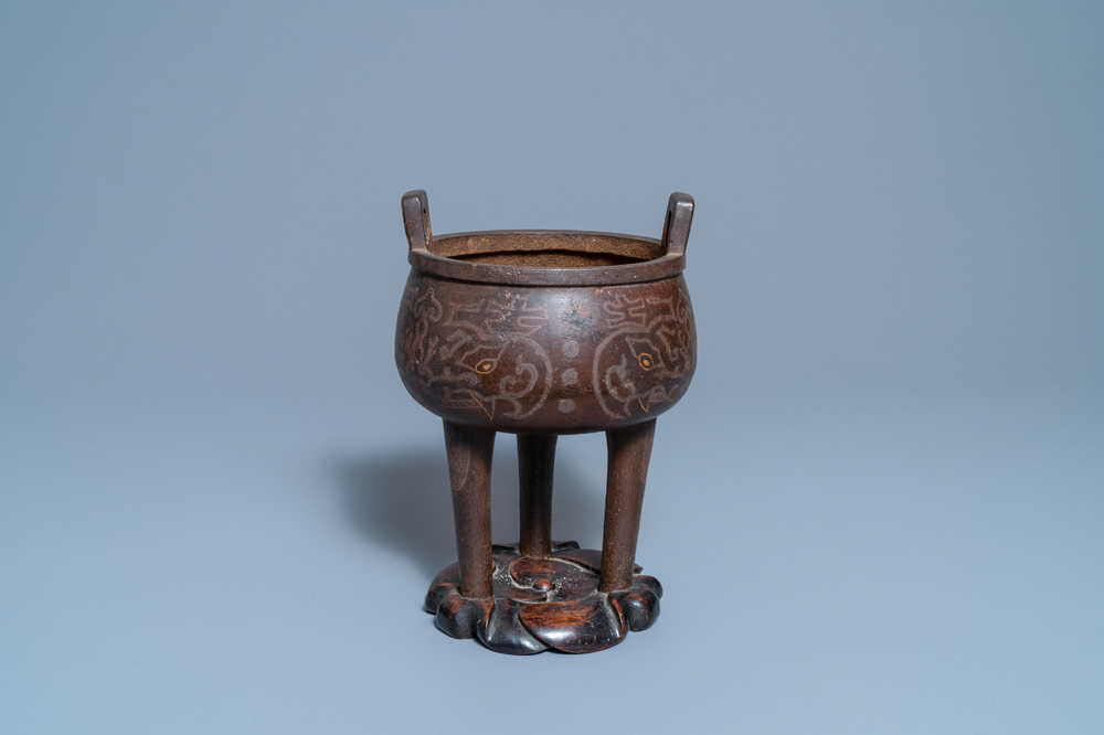 Een Chinese ingelegde bronzen driepotige wierookbrander op houten sokkel, Ming