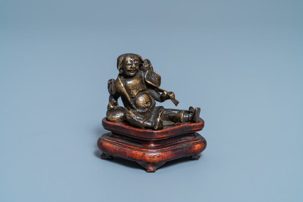 A Chinese bronze 'Liu Hai' scroll weight on wooden stand, Ming