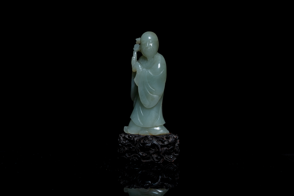 Een Chinese figuur van een onsterfelijke in celadon jade op houten sokkel, Qing