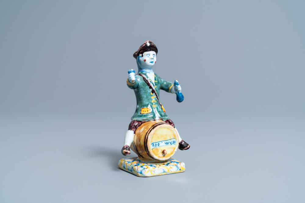 A polychrome Dutch Delft figure of a wine drinker on a barrel inscribed 'Rood Wyn', 18th C.