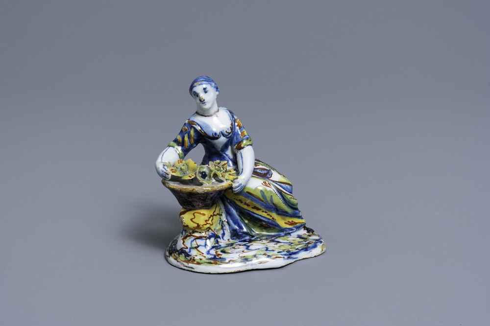A polychrome Dutch Delft figure of a lady selling flowers, 18th C.