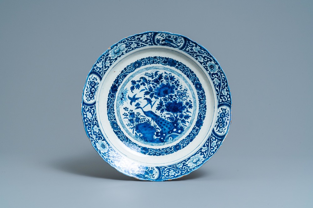 Un plat en fa&iuml;ence de Delft en bleu et blanc &agrave; d&eacute;cor d'un paon dans un jardin chinois, dat&eacute; 1693