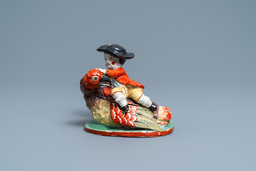 A polychrome Dutch Delft box and cover in the shape of a boy on a bird, 18th C.