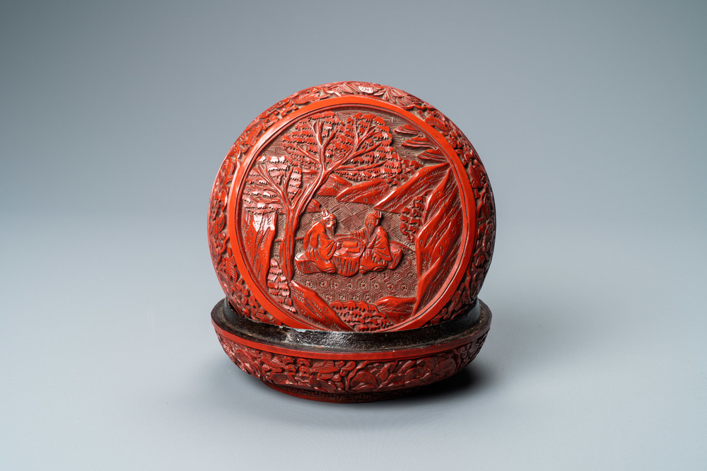 A Chinese round cinnabar lacquer box and cover with two scholars at a table, 18/19th C.