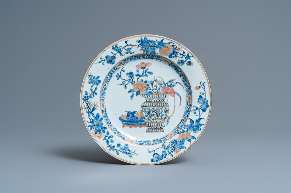 Une assiette en porcelaine de Chine en famille rose et grisaille &agrave; d&eacute;cor d'un vase fleuri et de fruits, Yongzheng