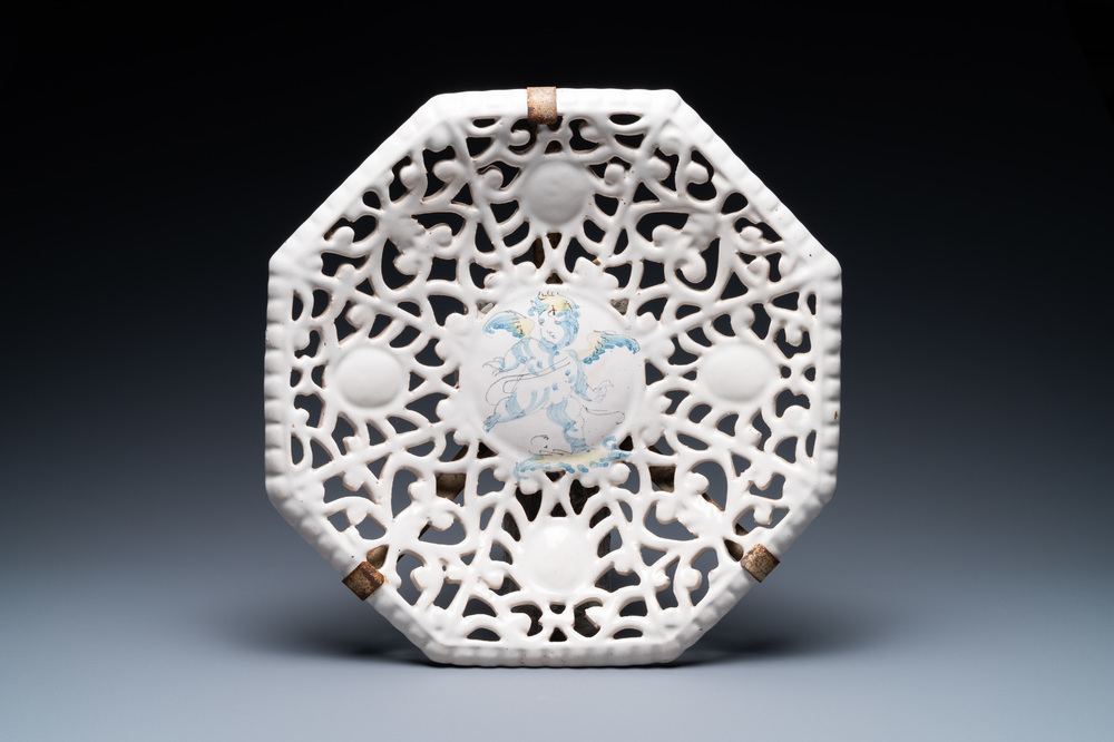 Een opengewerkte octagonale Italiaanse blauw-witte en gele tazza met een putto, Faenza, 17e eeuw