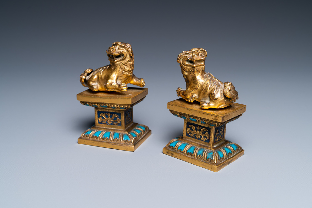 A pair of Chinese gilt bronze Buddhist lions on champlev&eacute; enamel bases, 18/19th C.