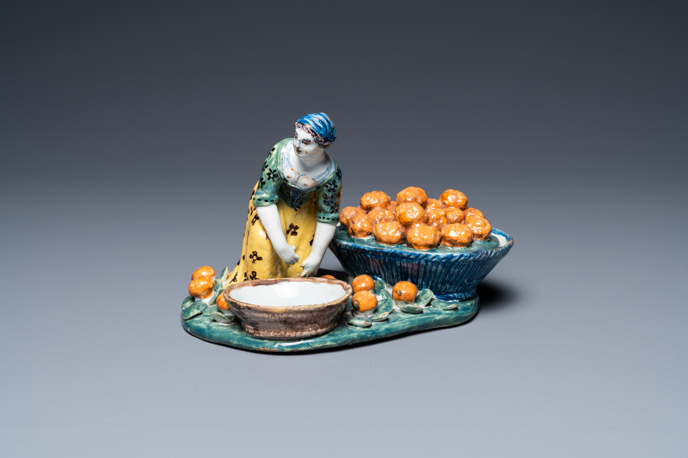 A polychrome Dutch Delft figure of a fruit seller with a small tureen, 18th C.