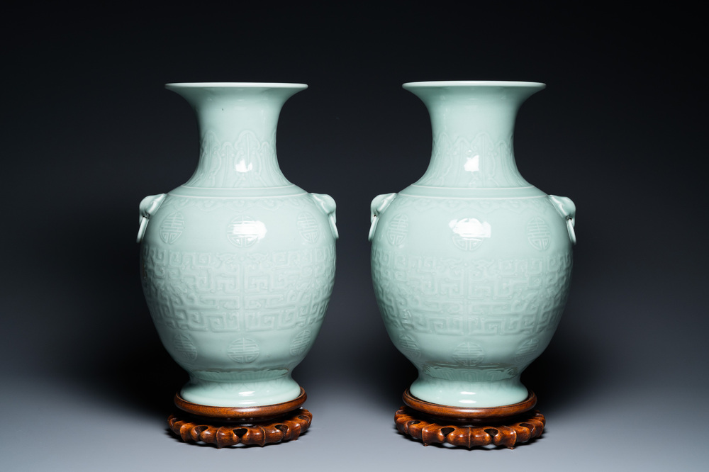A pair of Chinese monochrome celadon vases with underglaze design on wooden stands, Qianlong mark, 18/19th C.