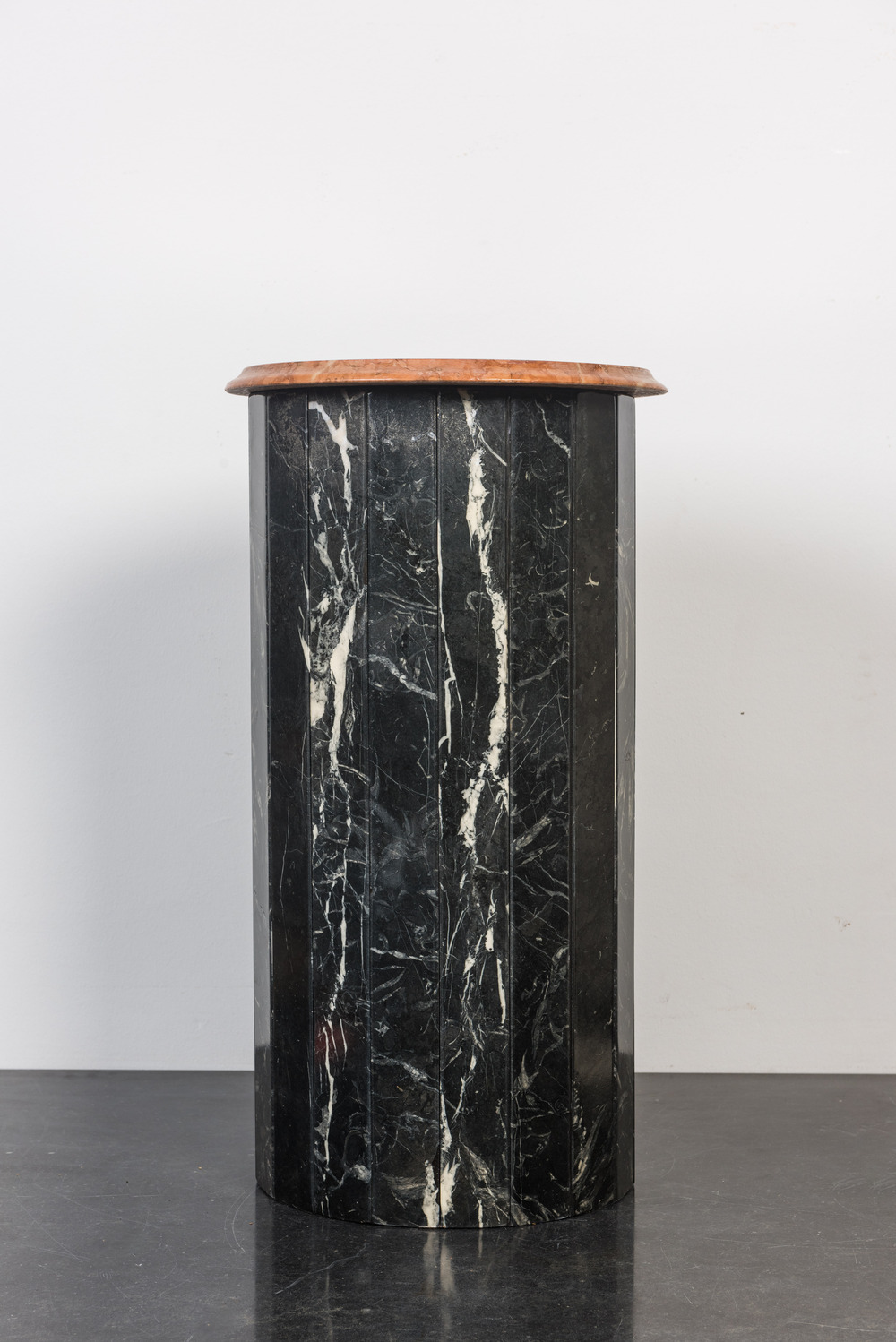 A black marble stand with orange-red marble top, 20th C.